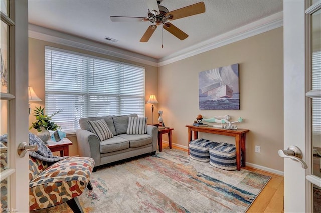 living room with visible vents, crown molding, baseboards, and wood finished floors