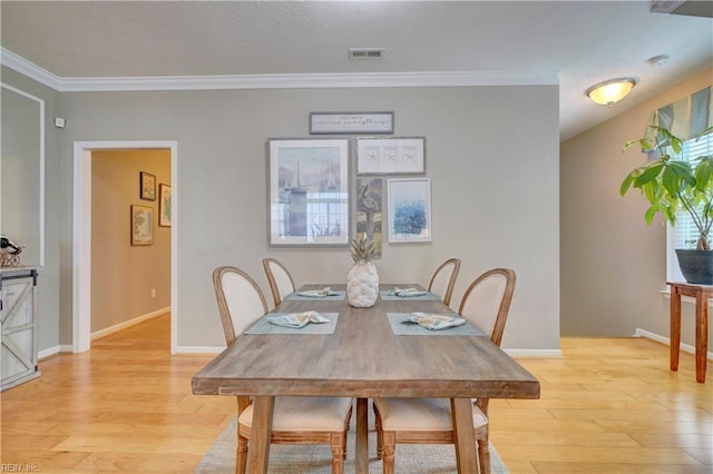 dining area featuring ornamental molding, baseboards, visible vents, and light wood finished floors