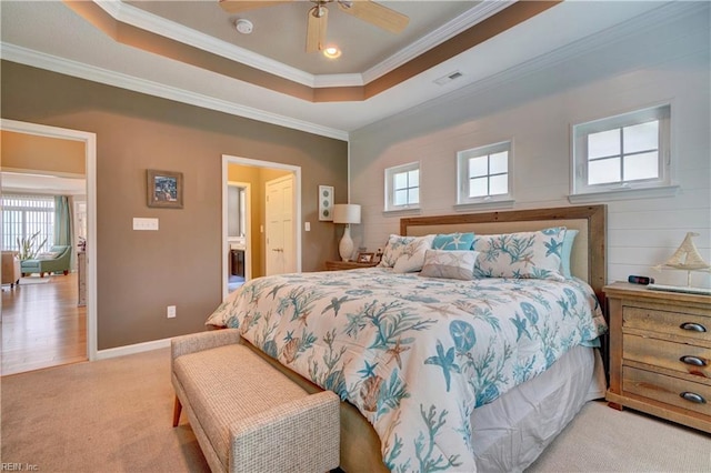 bedroom with a raised ceiling, light carpet, crown molding, and baseboards