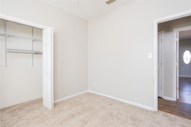 unfurnished bedroom with carpet, a closet, visible vents, and baseboards