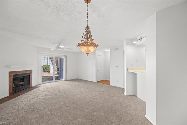 unfurnished living room featuring carpet floors, baseboards, a textured ceiling, and a tile fireplace