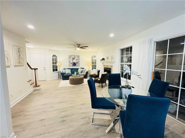 dining area featuring a ceiling fan, stairway, wood finished floors, a fireplace, and recessed lighting