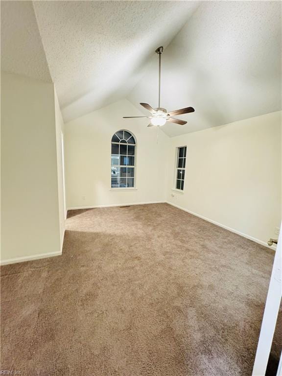 carpeted empty room with lofted ceiling, ceiling fan, a textured ceiling, and baseboards