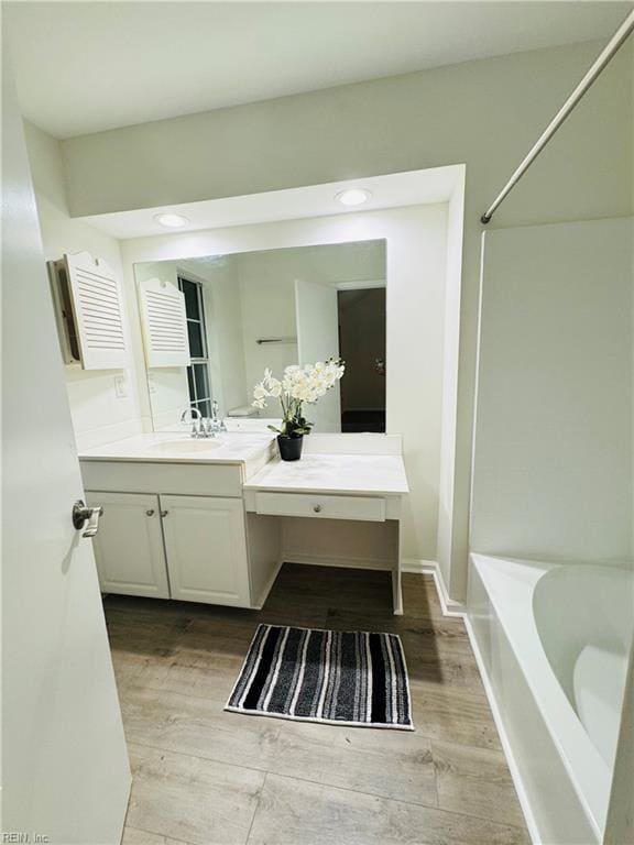 bathroom featuring washtub / shower combination, baseboards, wood finished floors, and vanity