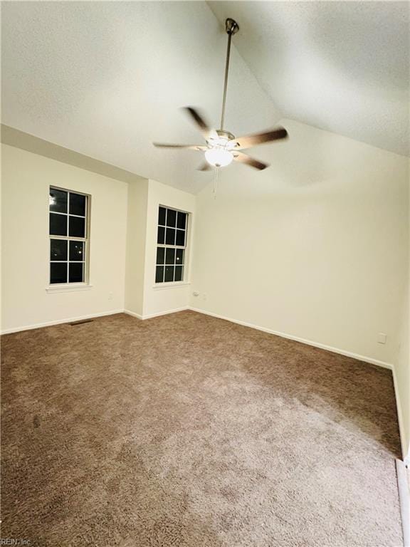 carpeted spare room with vaulted ceiling, ceiling fan, a textured ceiling, and visible vents