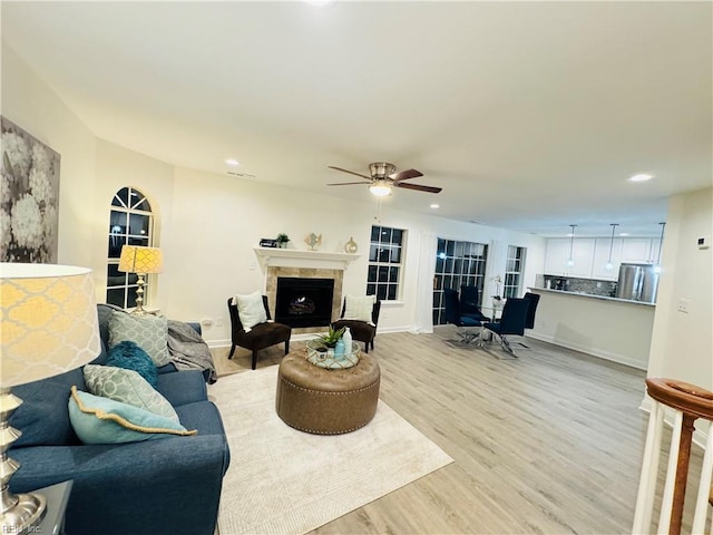 living area with light wood-type flooring, a tile fireplace, and recessed lighting