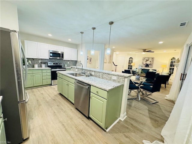 kitchen with visible vents, decorative backsplash, green cabinets, appliances with stainless steel finishes, and a sink