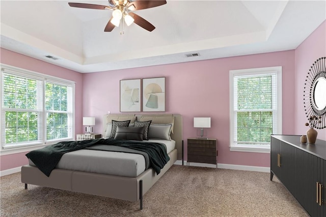 bedroom with light carpet, baseboards, visible vents, and a raised ceiling