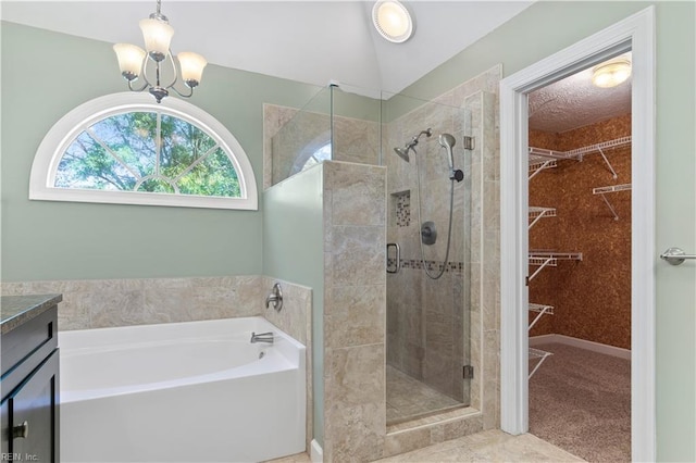 bathroom with a garden tub, vanity, a spacious closet, a shower stall, and an inviting chandelier