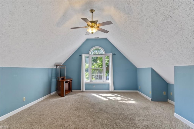 bonus room featuring carpet, vaulted ceiling, a textured ceiling, ceiling fan, and baseboards