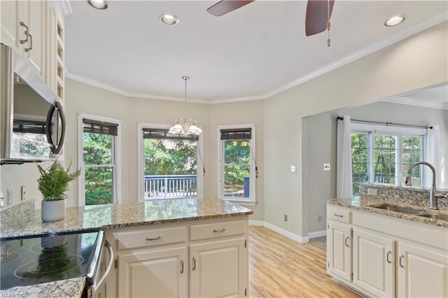 kitchen featuring stainless steel appliances, a sink, white cabinetry, ornamental molding, and light wood finished floors