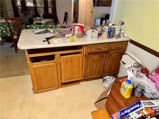 kitchen with brown cabinets, light countertops, a peninsula, and light floors