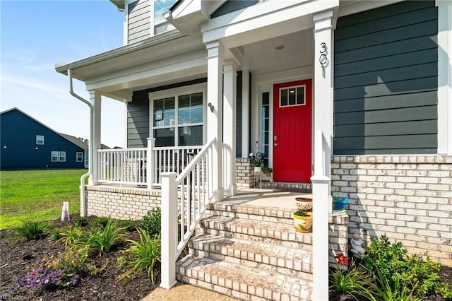 view of exterior entry featuring covered porch and a yard