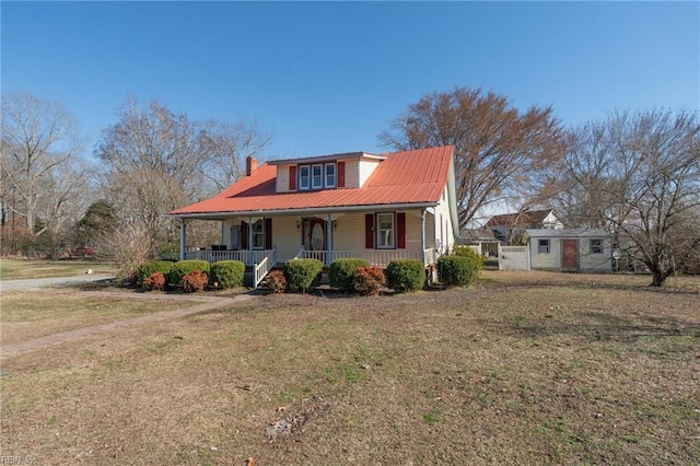 view of front facade with covered porch, metal roof, a front lawn, and a chimney