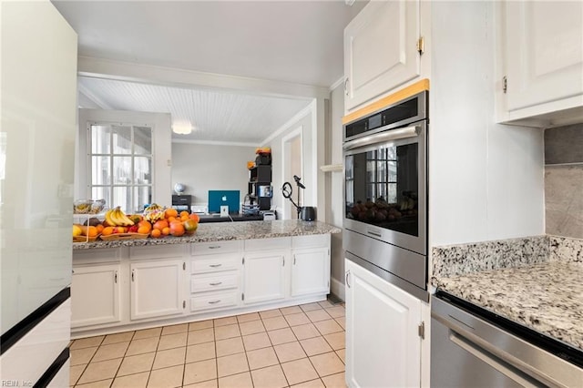 kitchen with light stone counters, light tile patterned floors, stainless steel appliances, open floor plan, and white cabinets