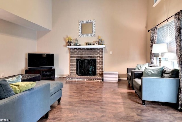 living room with a high ceiling, a fireplace, wood finished floors, and baseboards