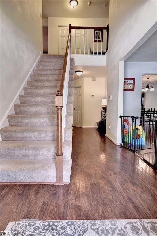 stairs featuring a towering ceiling, baseboards, and wood finished floors