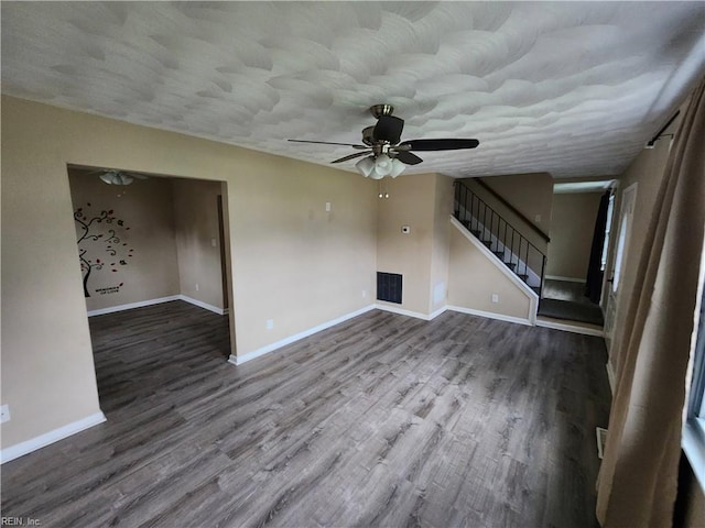 unfurnished living room featuring stairs, ceiling fan, wood finished floors, and baseboards