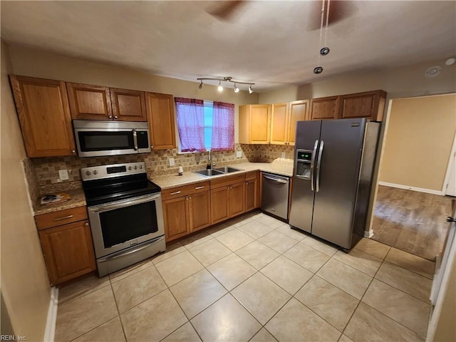 kitchen with brown cabinetry, appliances with stainless steel finishes, decorative backsplash, and a sink