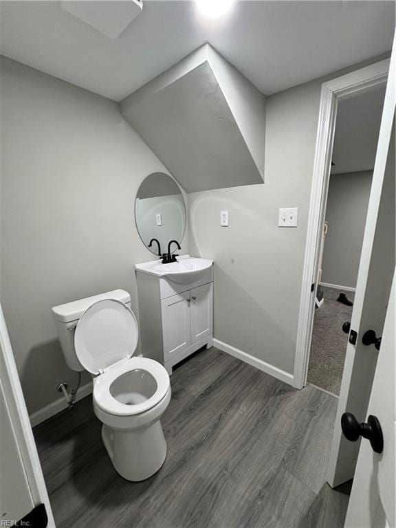 bathroom featuring toilet, baseboards, wood finished floors, and vanity