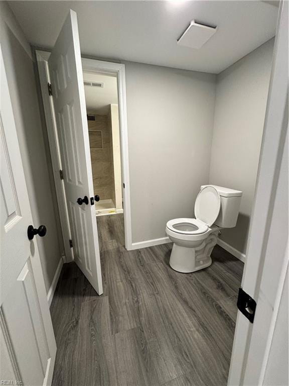 bathroom with visible vents, toilet, wood finished floors, baseboards, and walk in shower