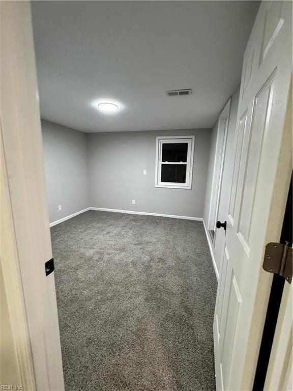 unfurnished room featuring visible vents, dark carpet, and baseboards