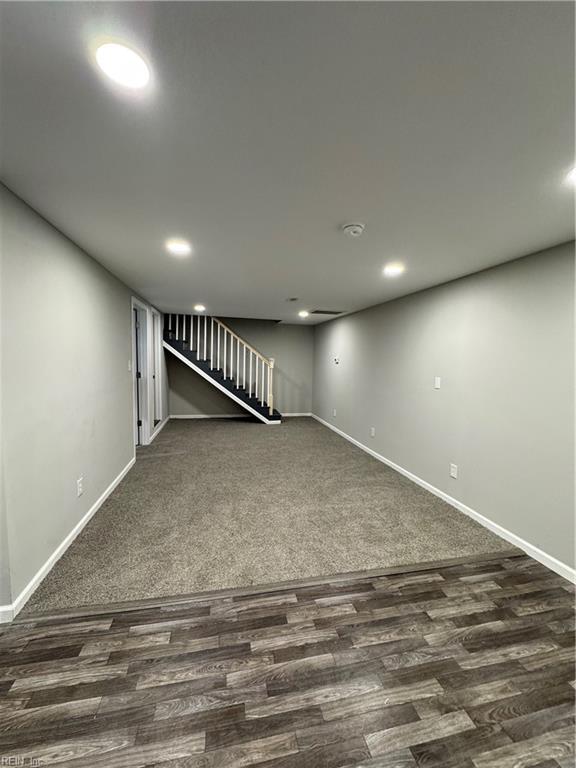 below grade area featuring stairs, baseboards, dark wood-type flooring, and recessed lighting