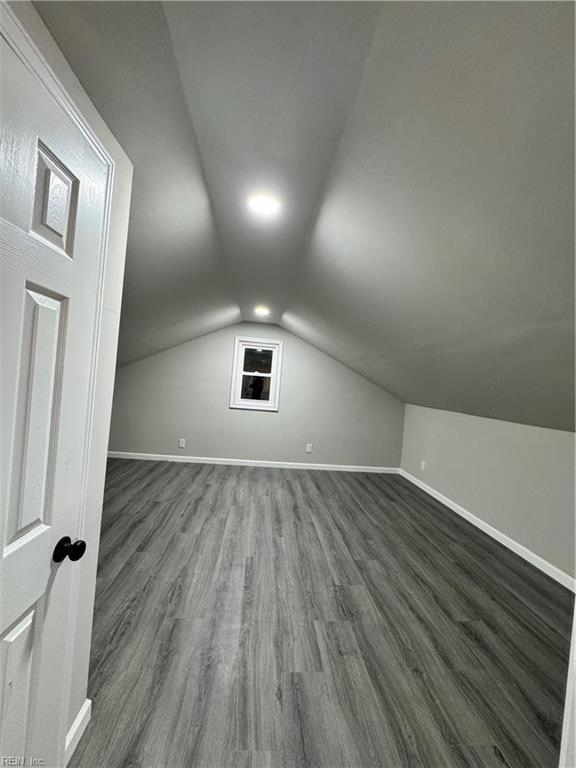 bonus room featuring dark wood finished floors, vaulted ceiling, and baseboards