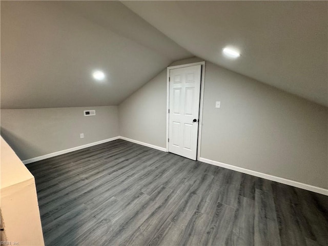 additional living space featuring lofted ceiling, dark wood-style floors, and baseboards