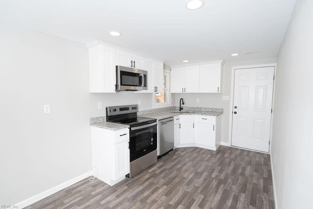 kitchen featuring stainless steel appliances, white cabinets, a sink, and dark wood-style floors