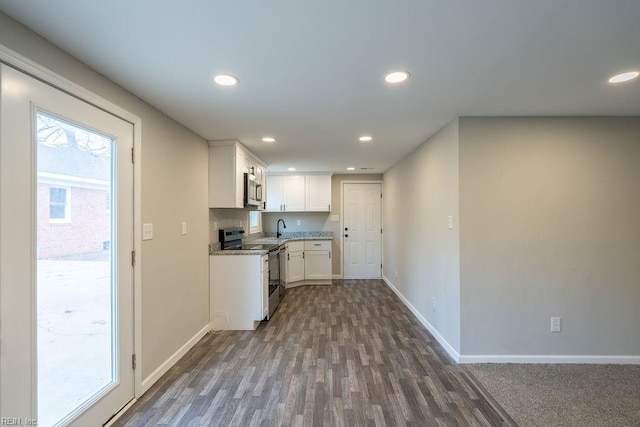 kitchen featuring recessed lighting, stainless steel appliances, a sink, baseboards, and white cabinets