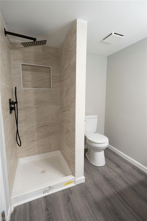 full bathroom featuring a stall shower, baseboards, visible vents, toilet, and wood finished floors