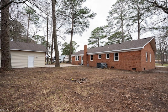 back of house with central AC, crawl space, brick siding, and a chimney