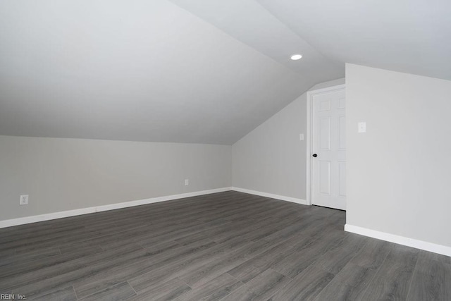 additional living space featuring dark wood-style floors, lofted ceiling, and baseboards