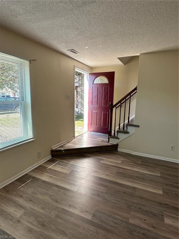 foyer entrance featuring baseboards, visible vents, stairway, and wood finished floors