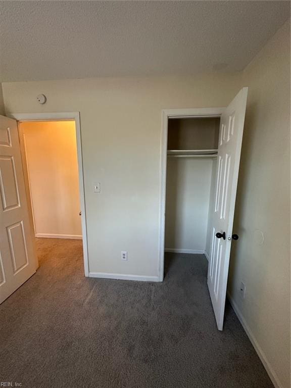 unfurnished bedroom featuring carpet, a closet, a textured ceiling, and baseboards