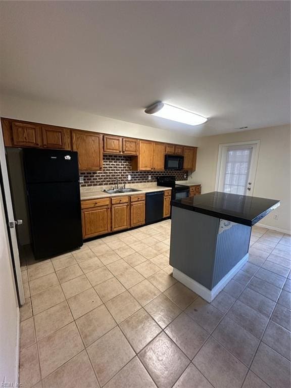 kitchen featuring decorative backsplash, brown cabinetry, light tile patterned flooring, a sink, and black appliances