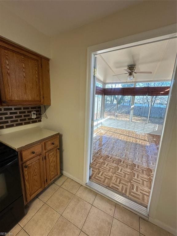 kitchen featuring light tile patterned floors, ceiling fan, electric range, and brown cabinetry