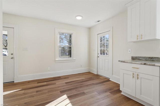 unfurnished dining area with baseboards, plenty of natural light, visible vents, and light wood-style floors