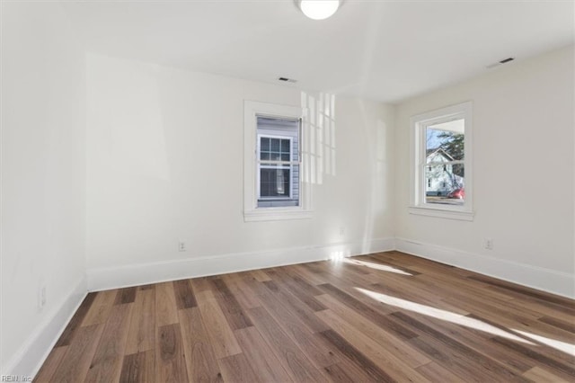 empty room with visible vents, baseboards, and wood finished floors