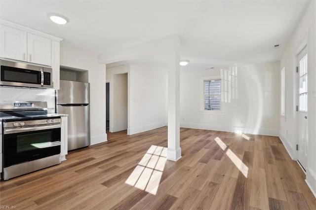 kitchen featuring light wood-type flooring, white cabinetry, stainless steel appliances, and a wealth of natural light