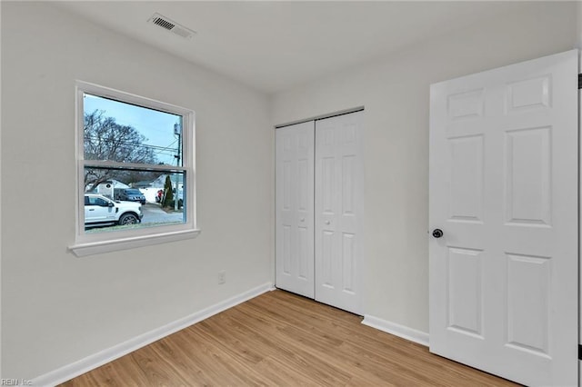 unfurnished bedroom featuring a closet, visible vents, light wood finished floors, and baseboards