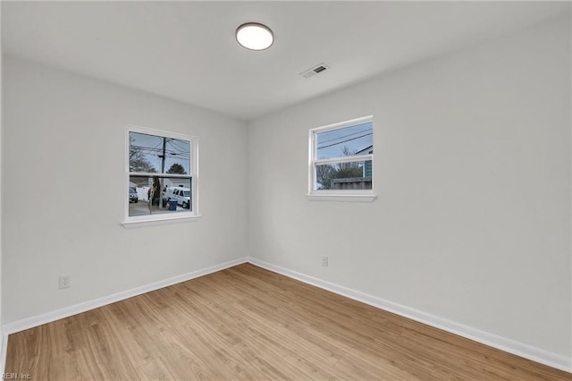 empty room with light wood-type flooring, visible vents, and baseboards