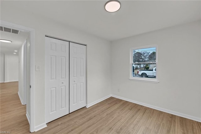 unfurnished bedroom with light wood finished floors, a closet, visible vents, and baseboards