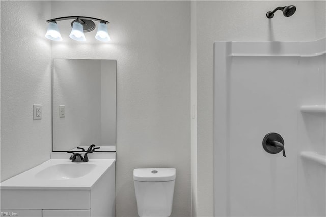 bathroom with toilet, walk in shower, and vanity