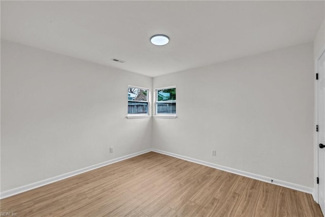 empty room featuring light wood finished floors, visible vents, and baseboards