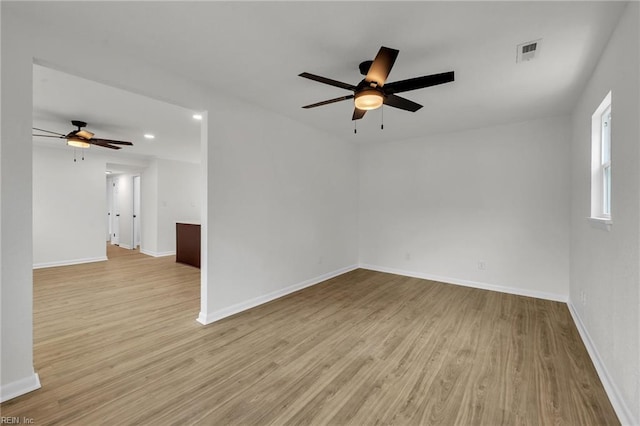 spare room featuring baseboards, visible vents, and wood finished floors