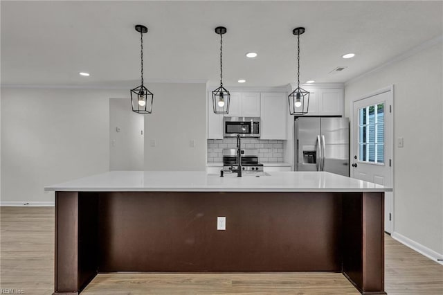 kitchen featuring stainless steel appliances, light countertops, backsplash, light wood-style floors, and ornamental molding