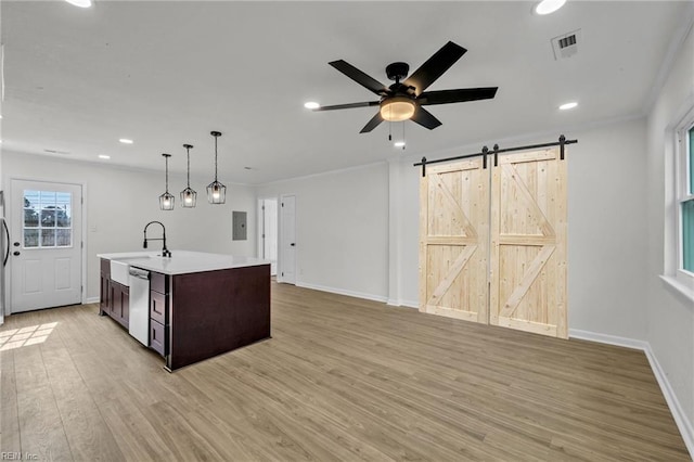 kitchen featuring a barn door, stainless steel appliances, visible vents, light wood-style floors, and light countertops