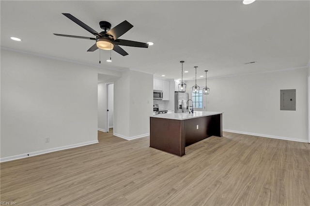 kitchen with appliances with stainless steel finishes, light wood-type flooring, open floor plan, and light countertops